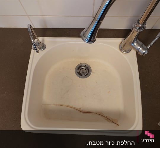 כיור עם משטח שיש כהה וברזים כסופים